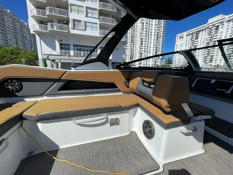 Slide: The Image of 2020 Scarab 285 ID boat interior with tan seating and modern design, docked near high-rise buildings. - 12