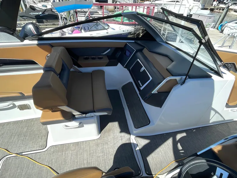 Slide: The Image of 2020 Scarab 285 ID boat interior with brown and white seating, dashboard, and open windshield. - 18