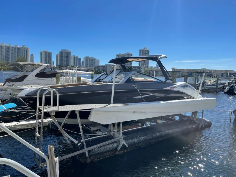 Slide: The Image of 2020 Scarab 285 ID boat docked at a marina with city skyline in the background. - 2