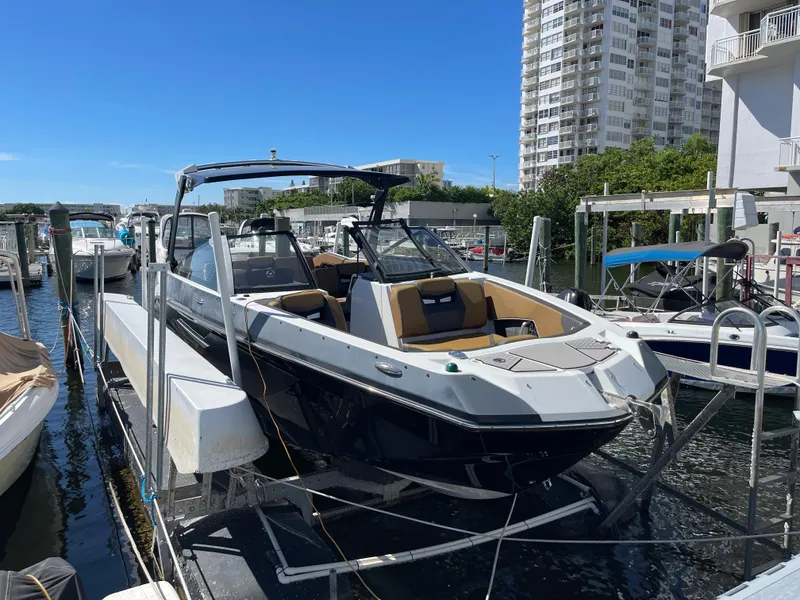 Slide: The Image of 2020 Scarab 285 ID boat docked at marina with modern buildings in background. - 4