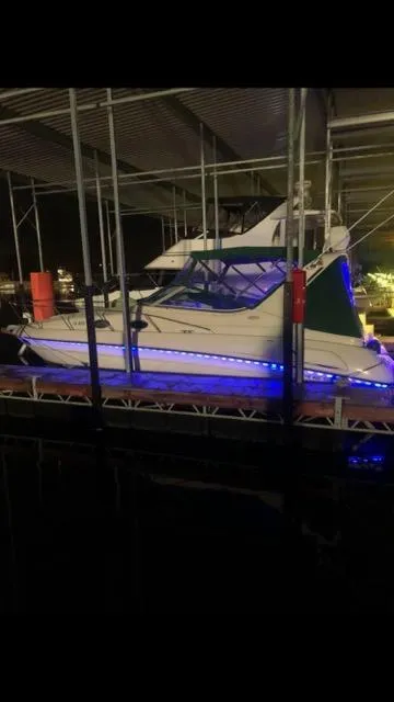 Slide: The Image of 1997 Regal 292 Commodore boat docked with blue LED lights at night. - 13