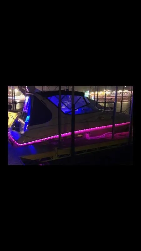 Slide: The Image of 1997 Regal 292 Commodore boat with vibrant blue and pink LED lights at night. - 14
