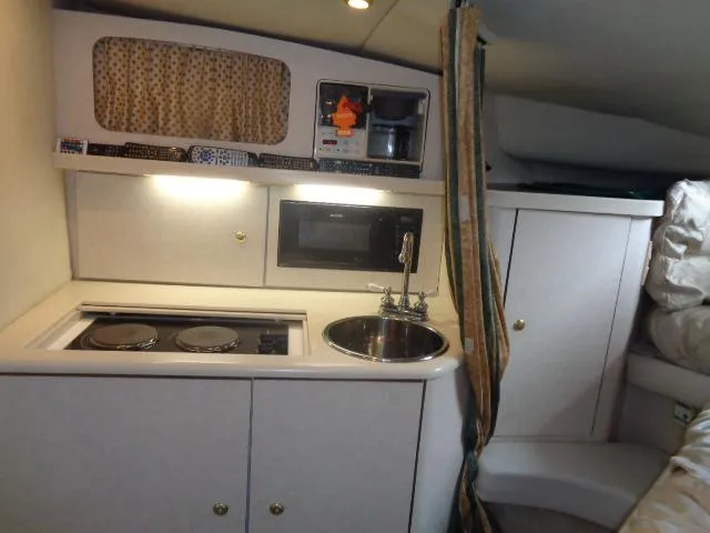 Slide: The Image of 1997 Regal 292 Commodore boat interior kitchen with stove, sink, and microwave. - 22