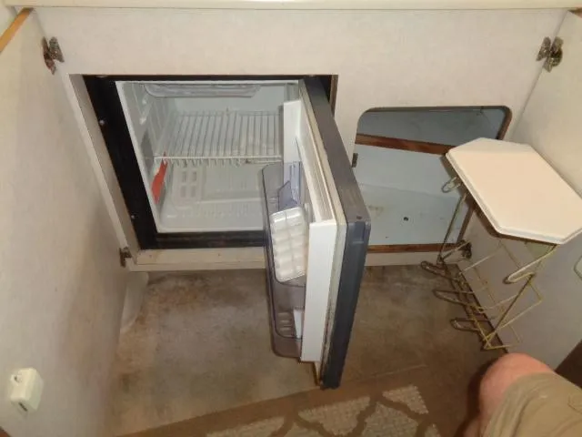 Slide: The Image of 1997 Regal 292 Commodore boat interior with open mini fridge and storage area. - 24