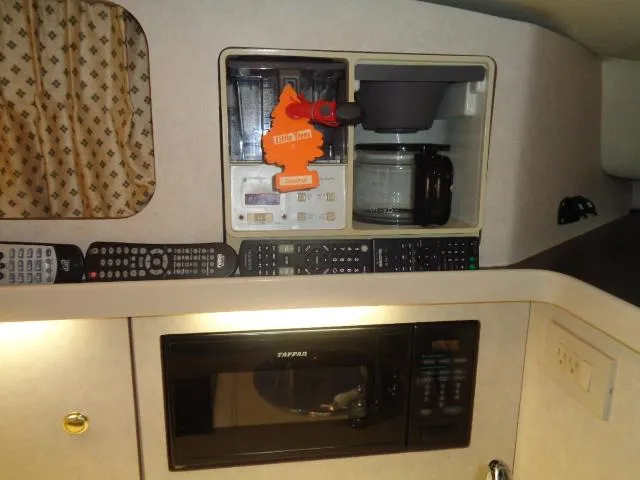 Slide: The Image of 1997 Regal 292 Commodore interior with microwave, coffee maker, and remote controls. - 25