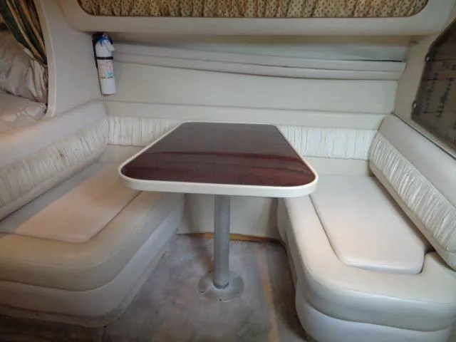 Slide: The Image of 1997 Regal 292 Commodore cabin dining area with cushioned seating and wooden table. - 29