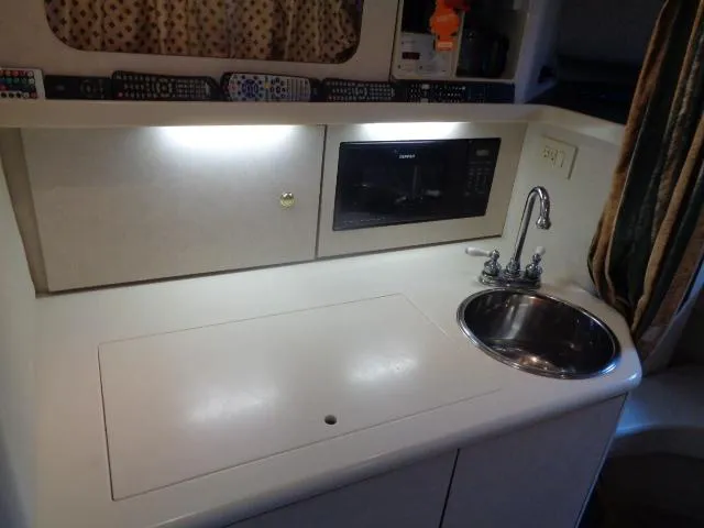 Slide: The Image of 1997 Regal 292 Commodore boat kitchenette with sink, microwave, and storage. - 32