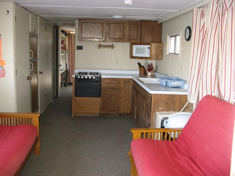 Slide: The Image of 1978 Kayot houseboat interior with kitchen, wooden cabinets, red futons, and striped curtains. - 15