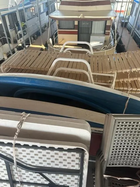 Slide: The Image of 1978 Kayot houseboat with deck chairs and tables, docked in a marina. - 18