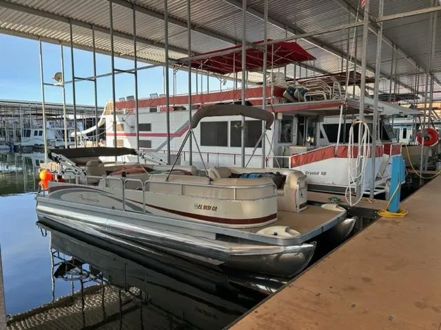 Slide: The Image of 1978 Kayot houseboat docked alongside a pontoon boat in a marina. - 2