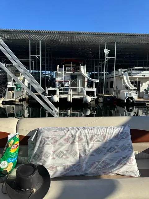 Slide: The Image of 1978 Kayot houseboat docked at marina, with cowboy hat and chips on deck. - 24