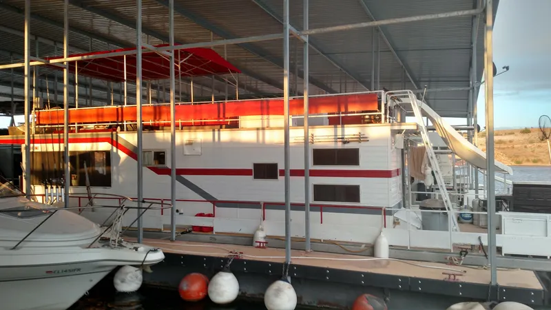 Slide: The Image of 1978 Kayot houseboat docked under a covered marina with a slide and vibrant red accents. - 32