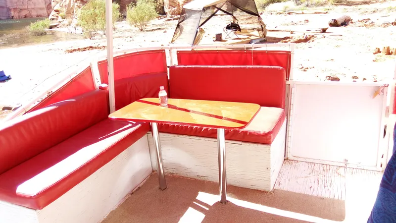 Slide: The Image of 1978 Kayot houseboat interior with red seating and table, set against a scenic outdoor backdrop. - 33