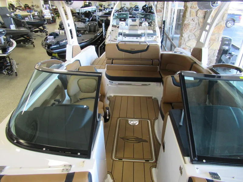 Slide: The Image of 2024 Chaparral 247 SSX boat interior with tan seating and dual windshields in showroom. - 6