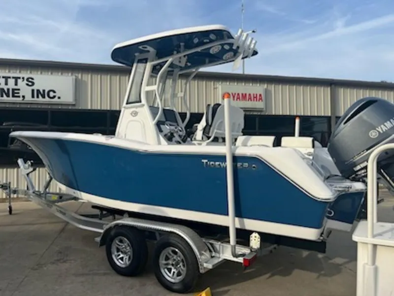 Slide: The Image of 2024 Tidewater 232 LXF boat on trailer, blue and white design, parked outside dealership. - 2