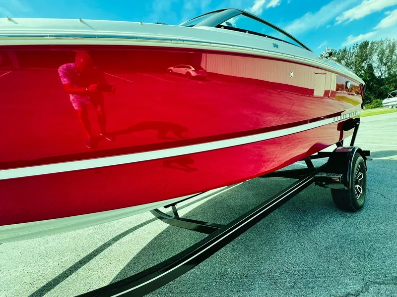 Slide: The Image of 2023 Four Winns H1 OB boat with a vibrant red hull on a trailer. - 5