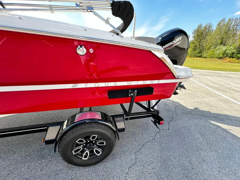 Slide: The Image of 2023 Four Winns H1 OB boat in red on a trailer with Mercury outboard motor. - 6