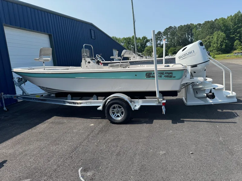 The Image of 2025 Carolina Skiff 192 JLS boat on trailer, parked outdoors near blue building. - 1