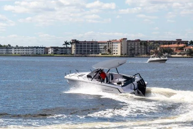 Slide: The Image of 2024 Axopar 25 Cross Top boat cruising on a sunny day near coastal buildings. - 10