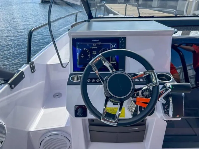 Slide: The Image of 2024 Axopar 25 Cross Top boat dashboard with steering wheel and digital display. - 13