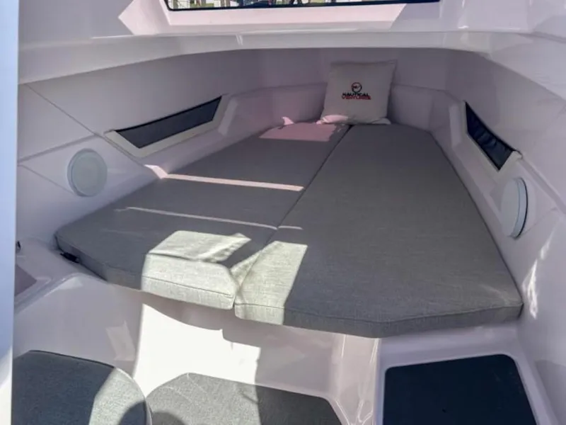 Slide: The Image of 2024 Axopar 25 Cross Top cabin interior with cushioned seating and windows. - 16