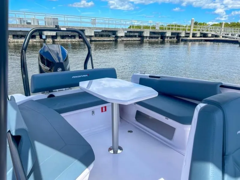Slide: The Image of 2024 Axopar 25 Cross Top boat with seating and table, docked by the water. - 19