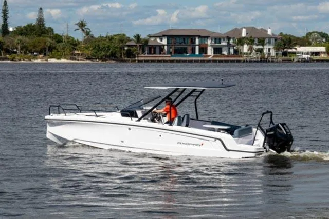 Slide: The Image of 2024 Axopar 25 Cross Top boat cruising on a scenic waterway. - 2