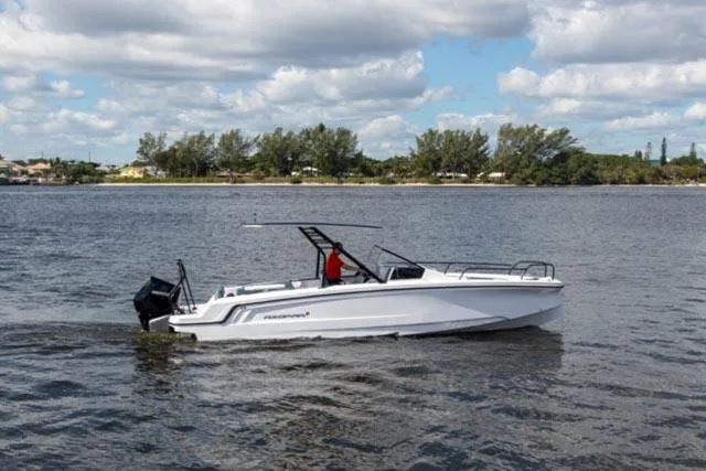 Slide: The Image of 2024 Axopar 25 Cross Top boat cruising on a calm lake under a cloudy sky. - 4