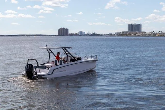 Slide: The Image of 2024 Axopar 25 Cross Top boat cruising on a sunny day near city skyline. - 7