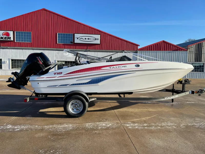 Slide: The Image of 2024 Tahoe T18 boat on trailer, parked outside red building. - 0