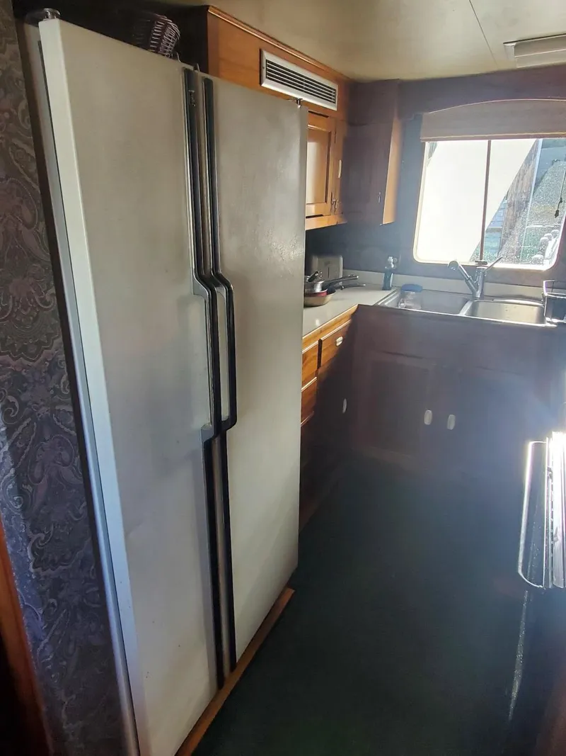 Slide: The Image of 1974 Stephens 68 Motor Yacht kitchen with refrigerator, sink, and wooden cabinets. - 12