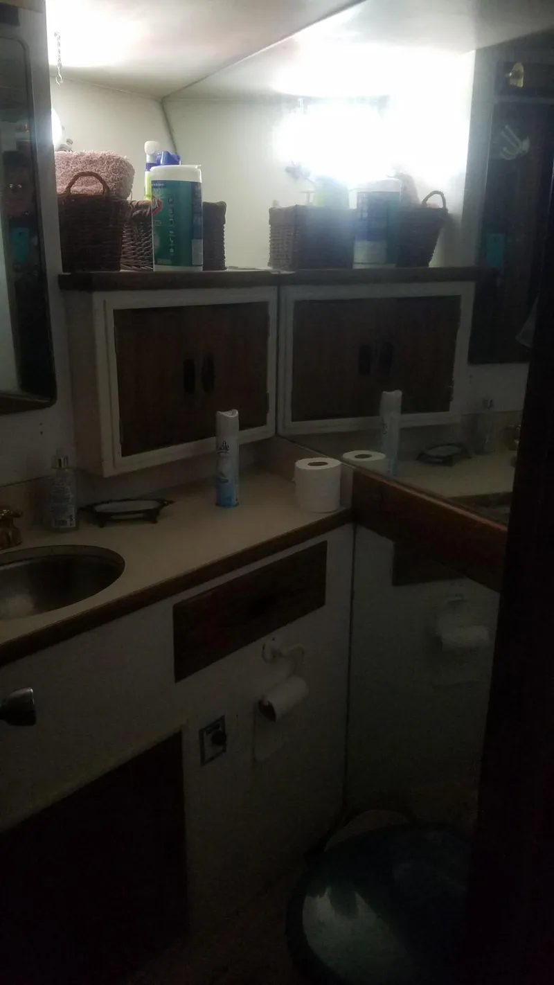Slide: The Image of 1974 Stephens 68 Motor Yacht bathroom with sink, storage cabinets, and toiletries. - 19