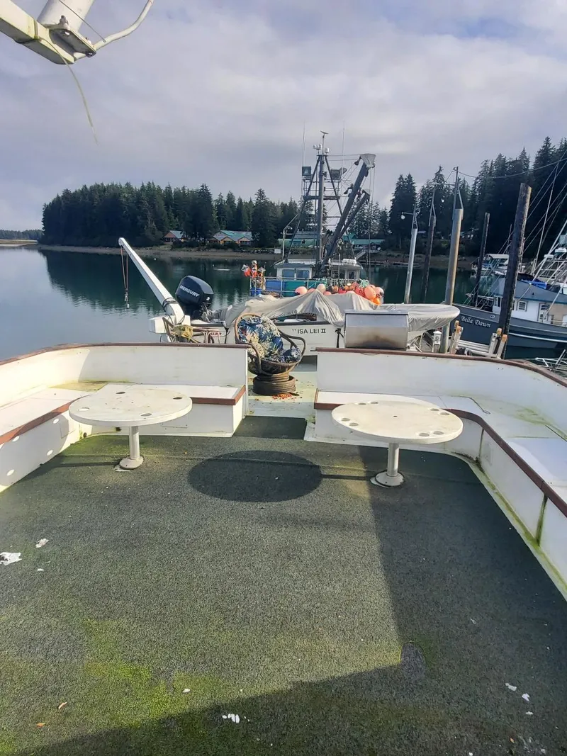 Slide: The Image of 1974 Stephens 68 Motor Yacht deck with seating, docked in a serene marina. - 7