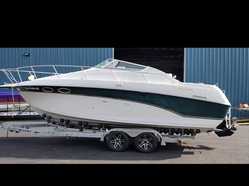 The Image of 1997 Crownline 250 CR boat on a trailer in front of a blue building. - 0