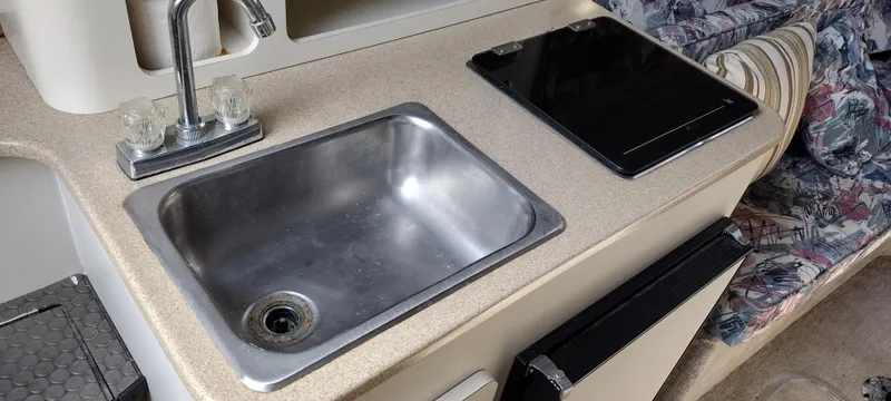 Slide: The Image of 1997 Crownline 250 CR boat kitchenette with sink, stove, and counter space. - 19