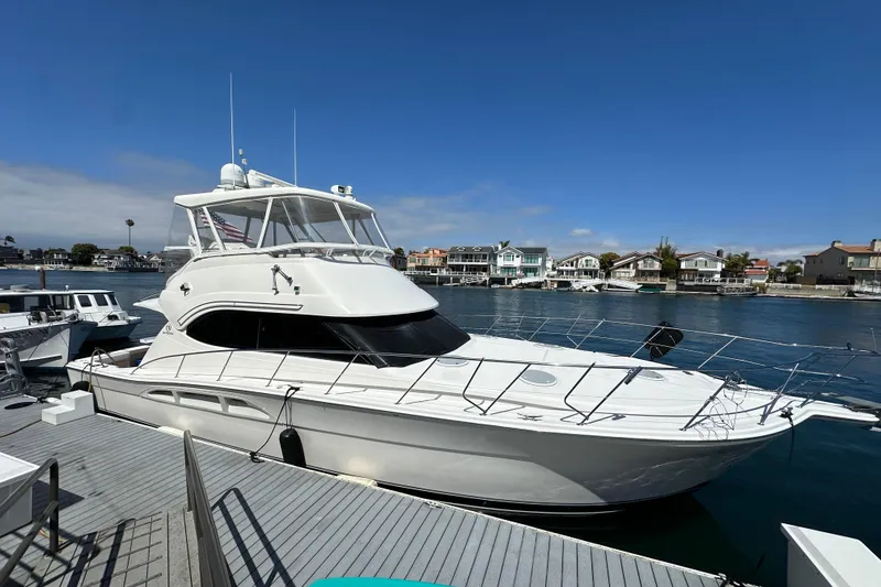 The Image of 2005 Riviera 47 Open Flybridge yacht docked in a scenic waterfront marina. - 0