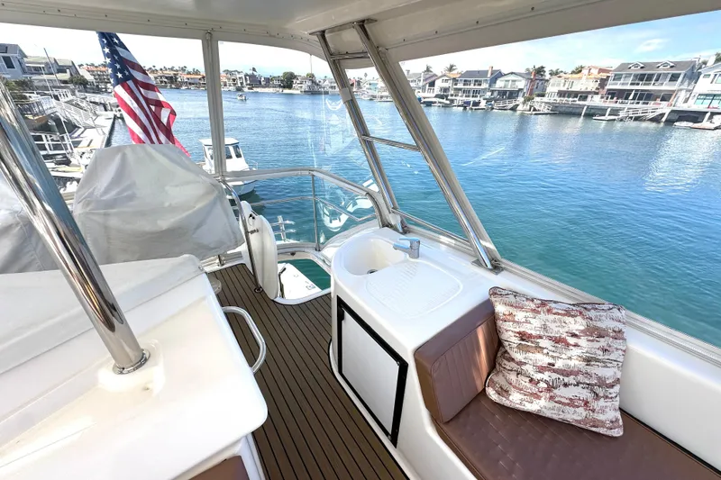 Slide: The Image of 2005 Riviera 47 Open Flybridge yacht interior with seating, sink, and waterfront view. - 13