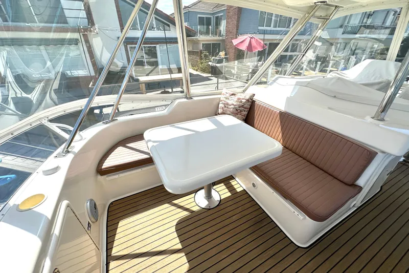 Slide: The Image of 2005 Riviera 47 Open Flybridge interior with seating and table, featuring teak flooring. - 15