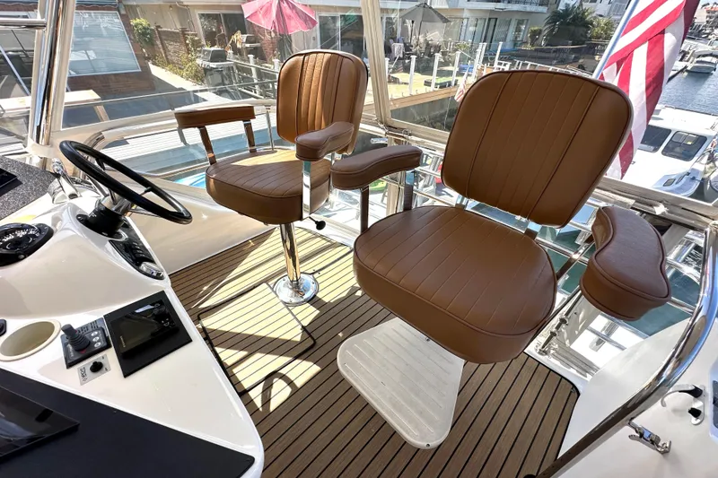 Slide: The Image of 2005 Riviera 47 Open Flybridge helm with brown leather seats and modern controls. - 16