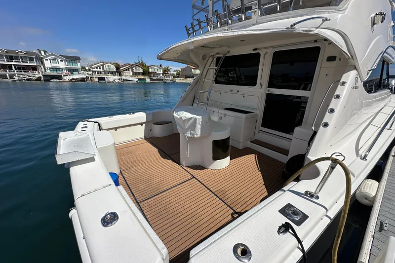 Slide: The Image of 2005 Riviera 47 Open Flybridge yacht with spacious deck, docked in a serene waterfront setting. - 54