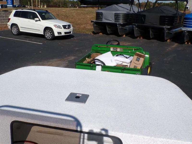 Slide: The Image of 2024 Custom 1800 Tunnel boat in parking lot with white SUV and green utility vehicle. - 14