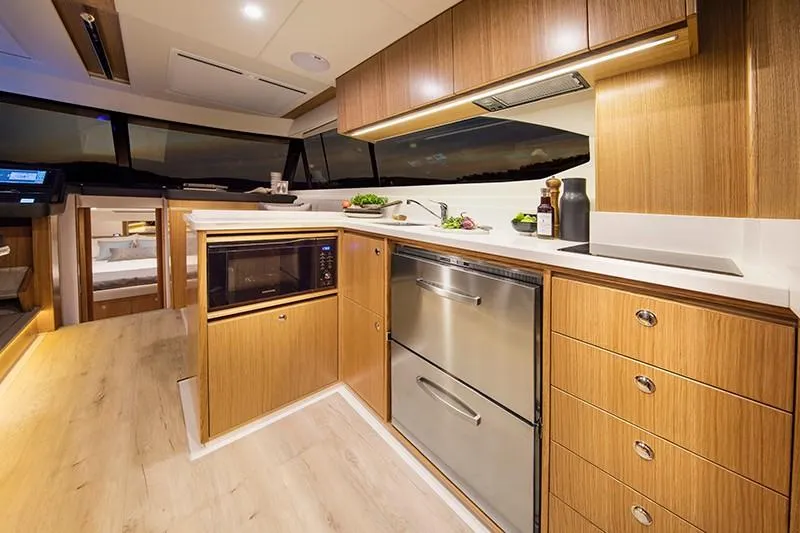 Slide: The Image of 2024 Riviera 395 SUV yacht kitchen with modern appliances and wooden cabinetry. - 10
