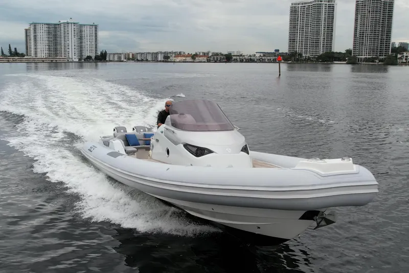 Slide: The Image of 2014 SACS Strider 13 boat cruising on water with city skyline in background. - 2