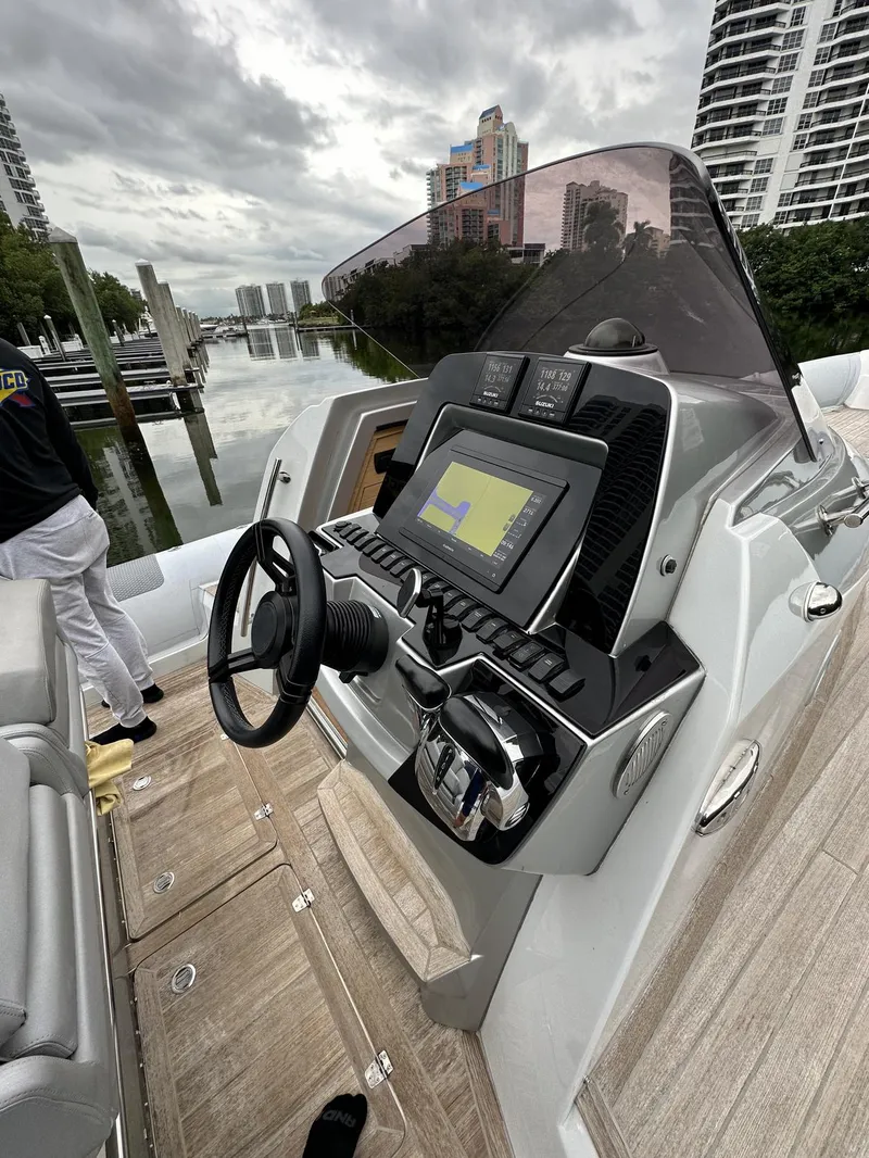 Slide: The Image of 2014 SACS Strider 13 boat dashboard with navigation system, docked near high-rise buildings. - 21
