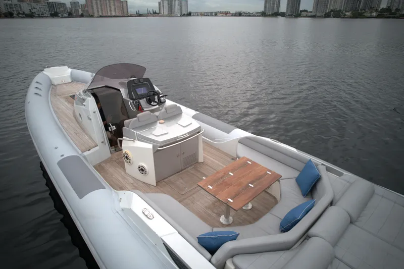 Slide: The Image of 2014 SACS Strider 13 luxury boat with seating area and navigation console on calm water. - 5