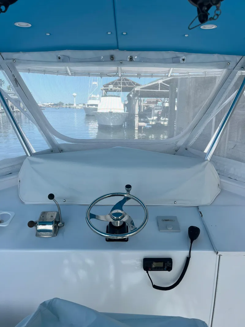 Slide: The Image of 1985 Custom Mabry Edwards boat cockpit with steering wheel and controls, docked at marina. - 6