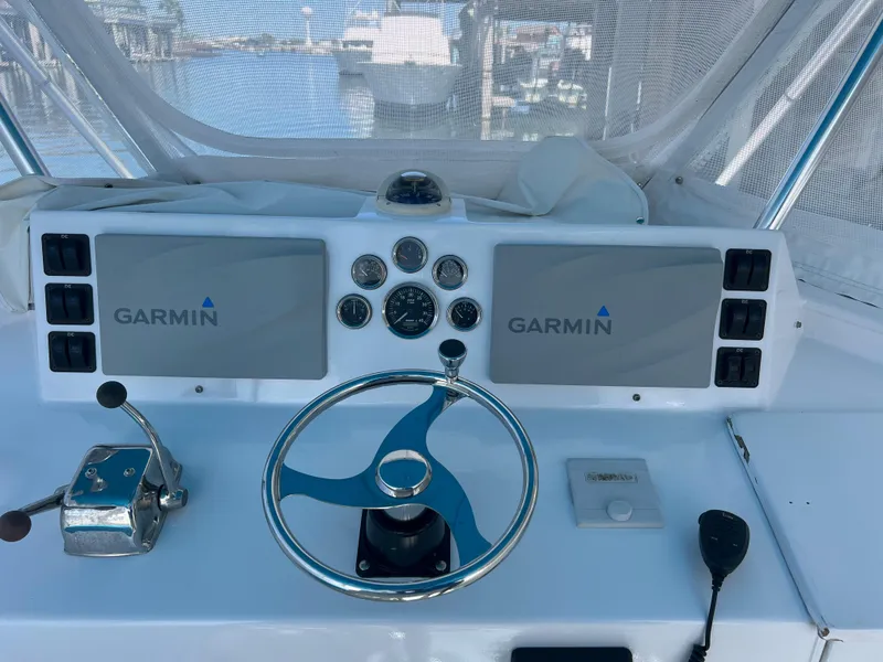 Slide: The Image of Boat helm with dual Garmin screens, steering wheel, and controls on a 1985 Custom Mabry Edwards. - 7