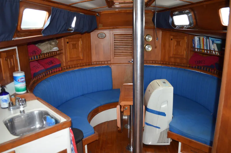 Slide: The Image of 1977 Cheoy Lee 41' Offshore yacht interior with blue seating, wooden cabinetry, and small kitchenette. - 13