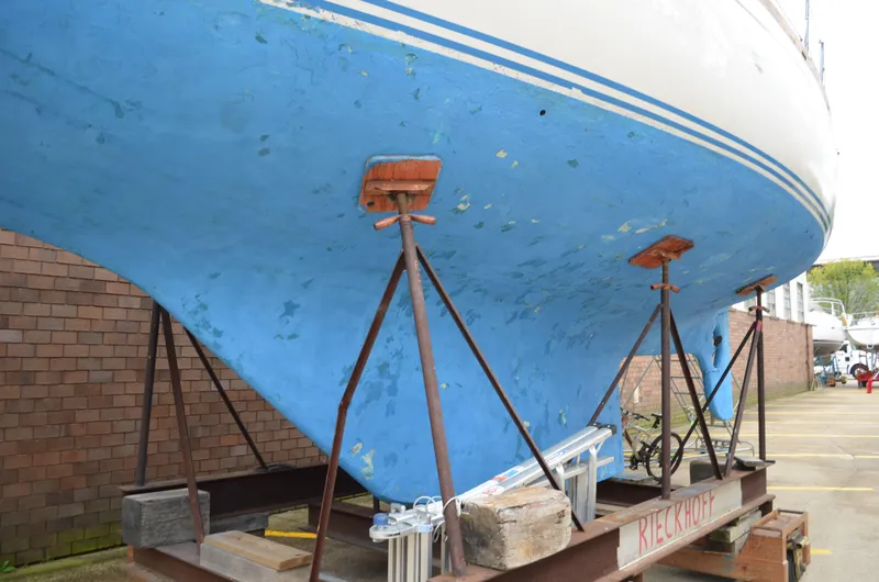 Slide: The Image of 1977 Cheoy Lee 41' Offshore sailboat on stands, blue hull, brick wall background. - 2