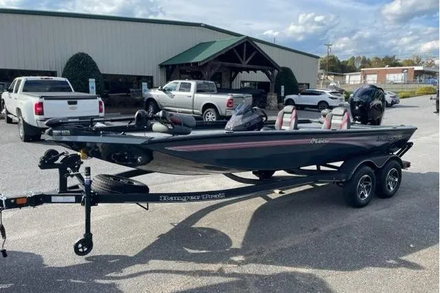 Slide: The Image of 2024 Ranger RT198P boat on trailer, parked outside dealership with trucks in background. - 9